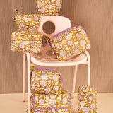 Collection de trousses Carthage Kaki de Byzantine, fleurs lilas sur fond kaki, sur une chaise rose