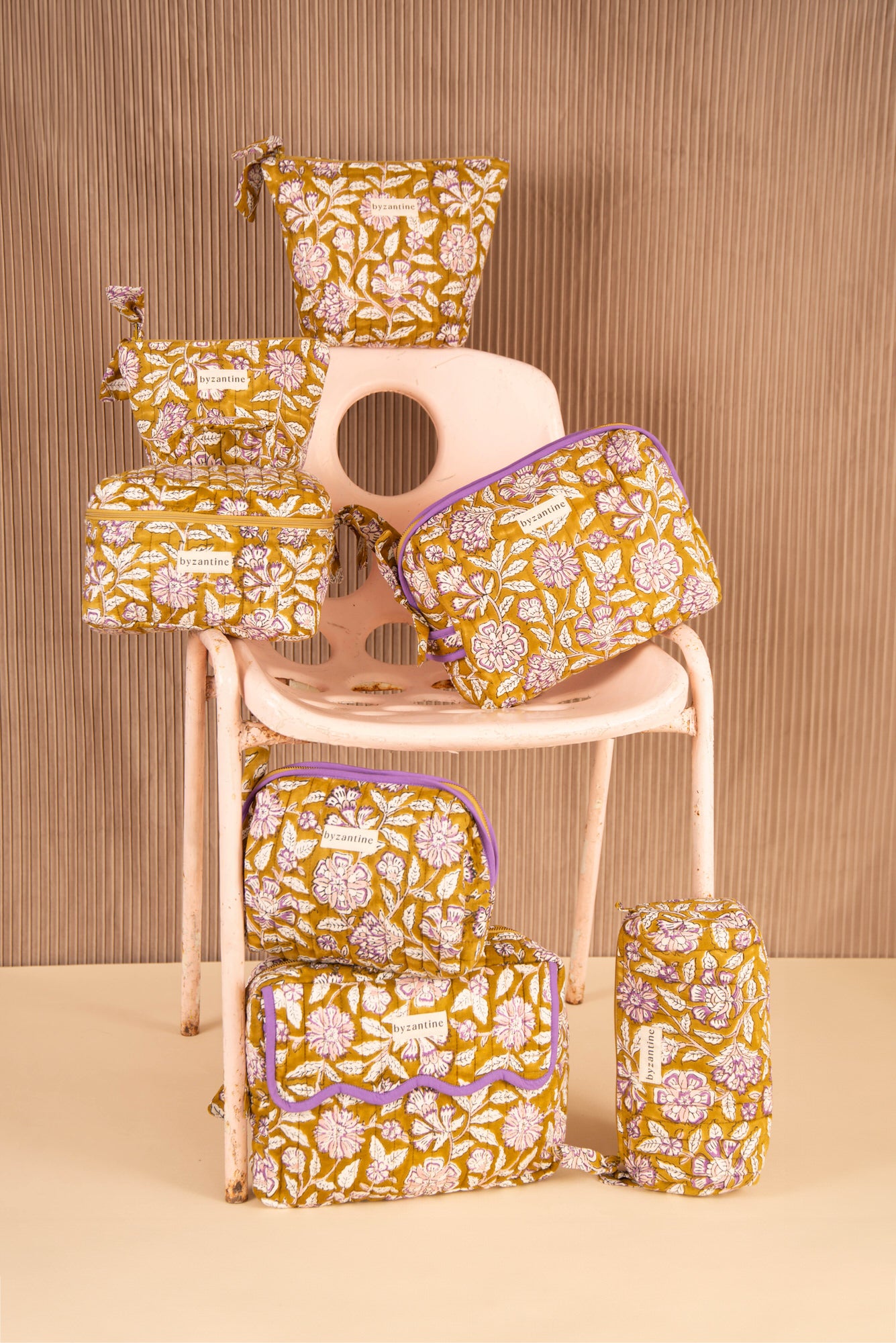 Collection de trousses Carthage Kaki de Byzantine, fleurs lilas sur fond kaki, sur une chaise rose