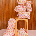 Collection de trousses Éphèse Rose de Byzantine, fleurs rose et orangé, sur un tabouret