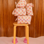 Trousses Éphèse Rose empilées sur un tabouret en bois aux pieds roses