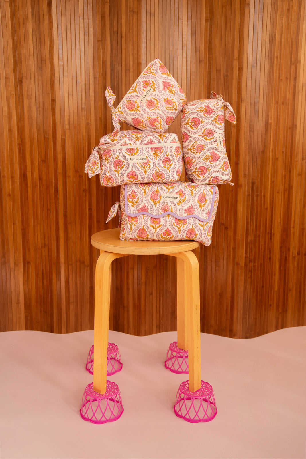 Trousses Éphèse Rose empilées sur un tabouret en bois aux pieds roses