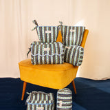 Collection de trousses Flora Bleu marine de Byzantine, rayures fleuries, sur un fauteuil moutarde