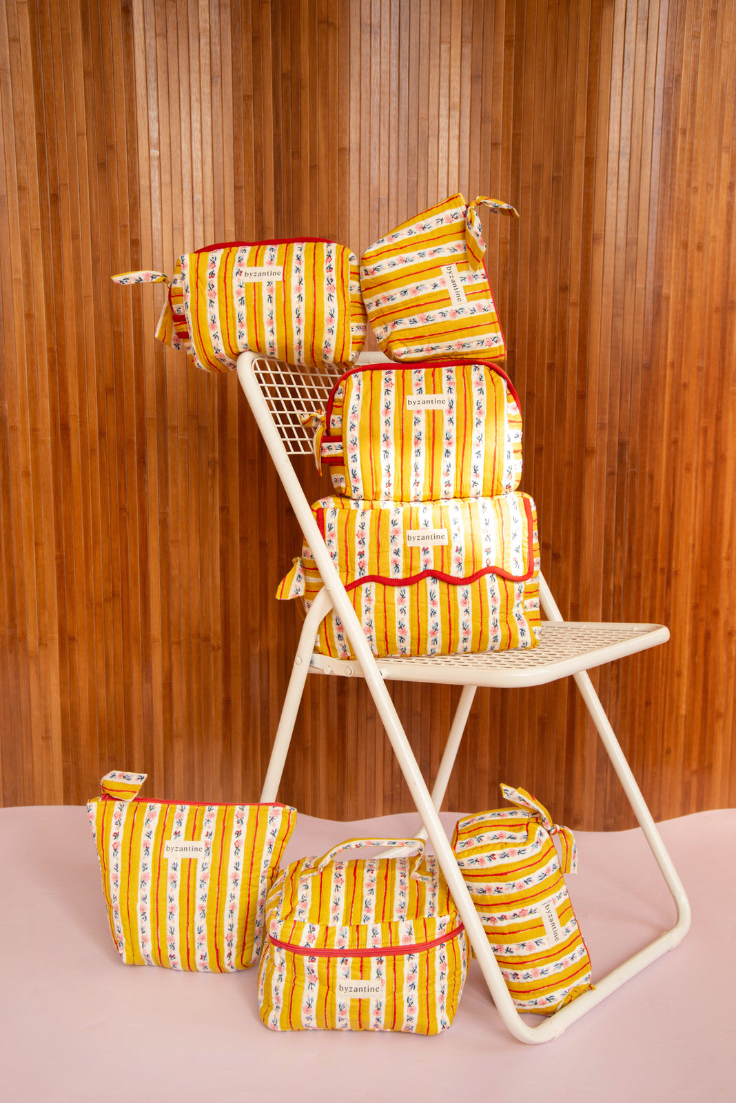 Collection de trousses Flora Passion de Byzantine, rayures fleuries jaunes, sur une chaise blanche