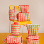 Collection de trousses Flora Rose de Byzantine, rayures fleuries rose et rouge, sur une chaise jaune