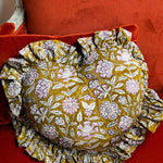 Coussin cœur Carthage Kaki de byzantine, imprimé fleuri kaki et blanc à volants, sur un canapé rouge