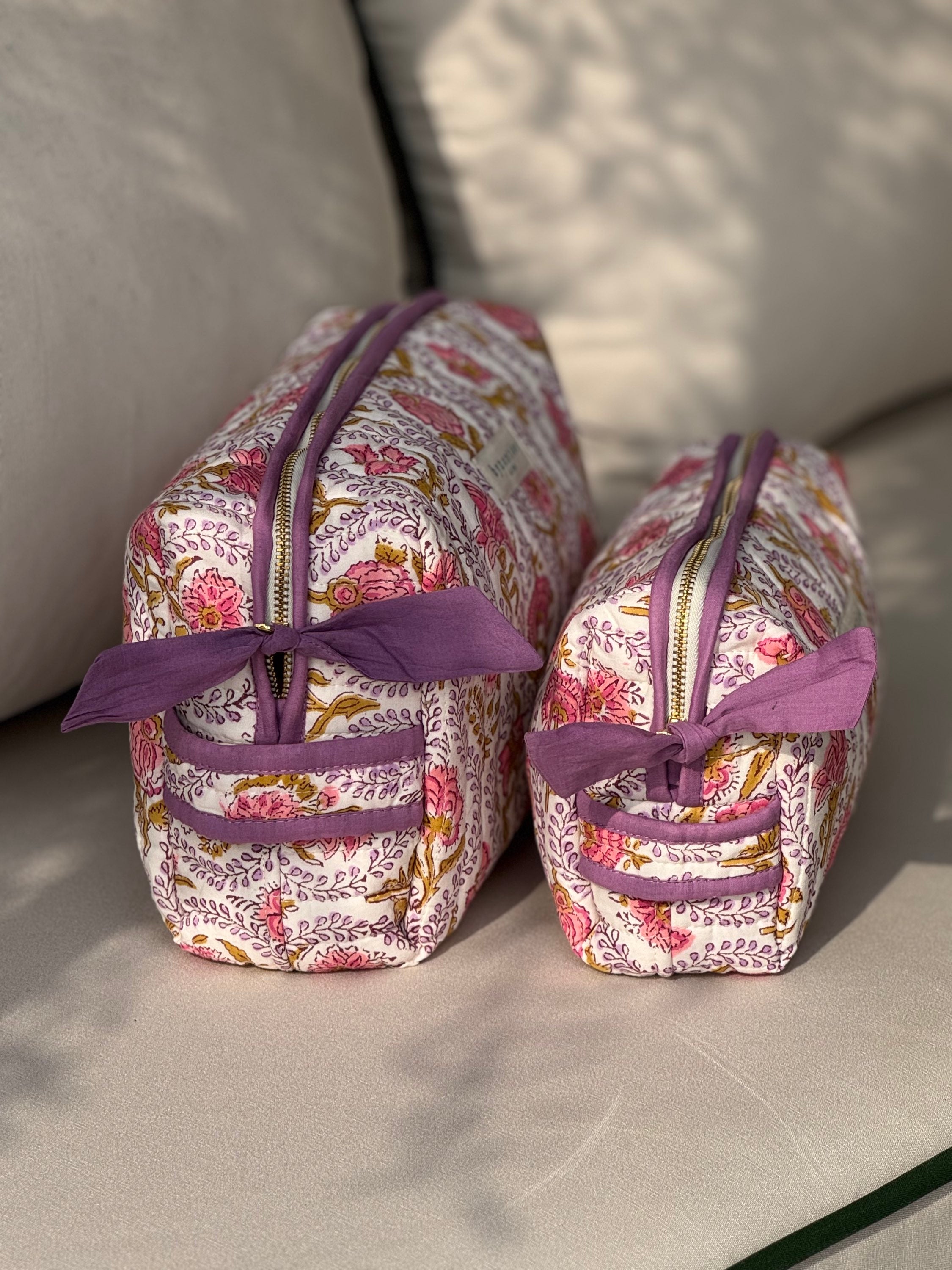 Trousses de toilette Éphèse Rose vues de côté, fermeture éclair et nœuds lilas