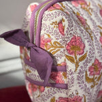 Gros plan sur la trousse de toilette Éphèse Rose de byzantine, fleurs roses et nœud lilas