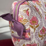 Gros plan sur la trousse de toilette Éphèse Rose de byzantine, fleurs roses et nœud lilas