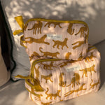 Grande et petite trousses de toilette Fauve Rose posées sur un coussin