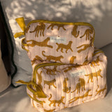 Grande et petite trousses de toilette Fauve Rose posées sur un coussin
