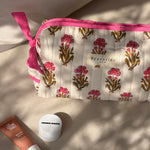 Trousse de toilette N°50 Rose posée sur un banc avec des produits de soin