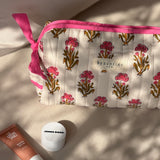 Trousse de toilette N°50 Rose posée sur un banc avec des produits de soin