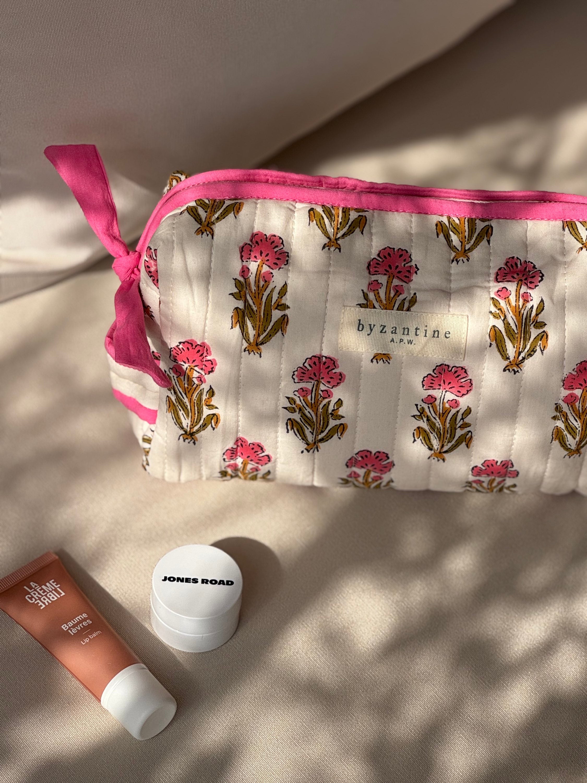 Trousse de toilette N°50 Rose posée sur un banc avec des produits de soin