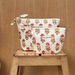 Grande et petite trousses beauté N°50 Rose, motif floral rose et jaune, sur un tabouret