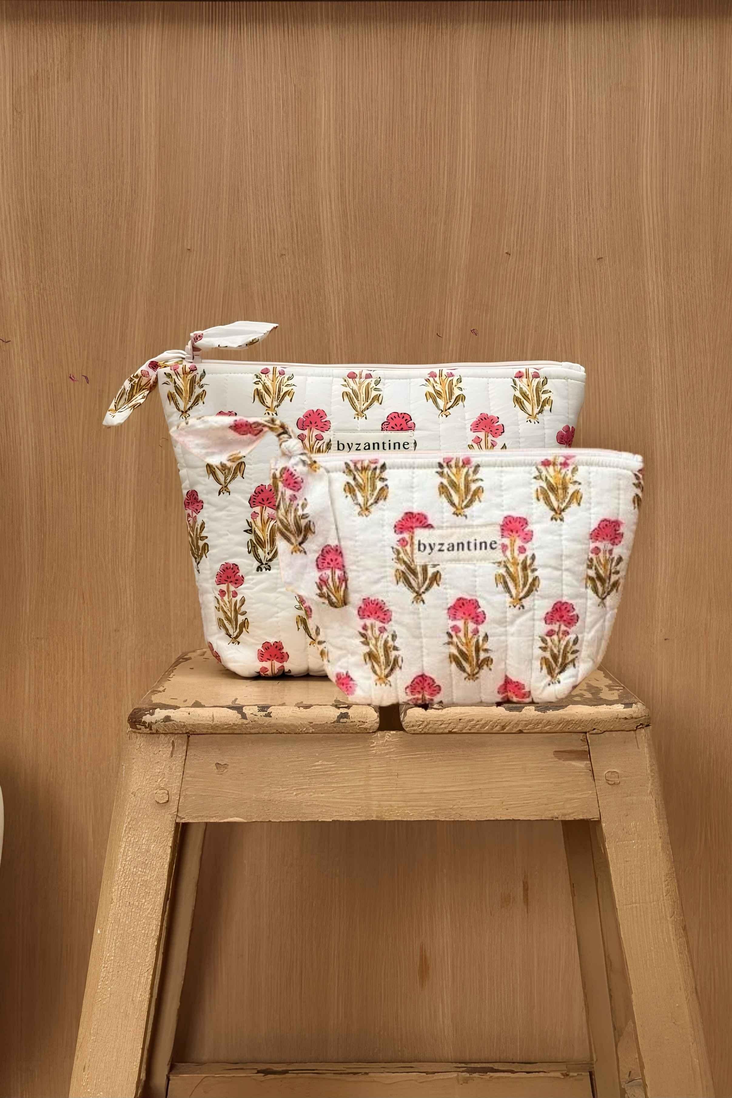 Grande et petite trousses beauté N°50 Rose, motif floral rose et jaune, sur un tabouret