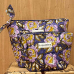 Duo de trousses beauté N°113 Bleu de byzantine, fleurs lilas et jaunes sur fond bleu, sur un tabouret
