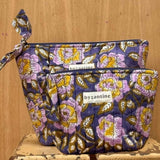 Duo de trousses beauté N°113 Bleu de byzantine, fleurs lilas et jaunes sur fond bleu, sur un tabouret