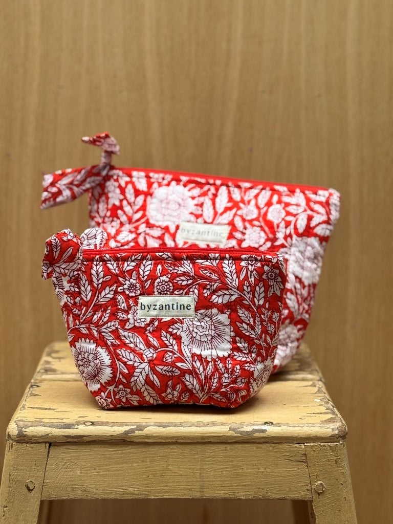 Duo de trousses beauté Antioche Tomato de byzantine, imprimé fleuri rouge et blanc, sur un tabouret