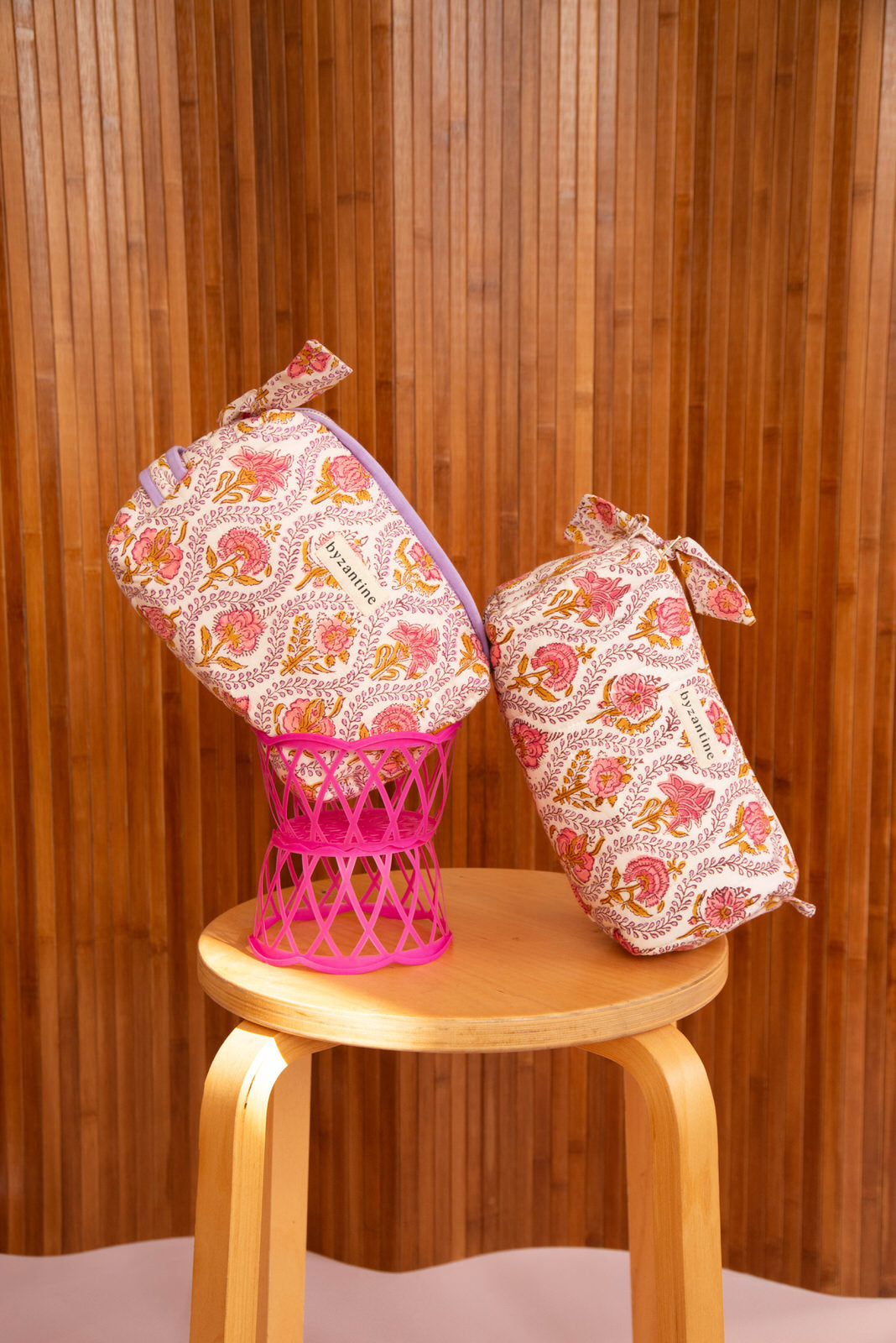 Duo de trousses beauté Éphèse Rose posées sur une corbeille rose