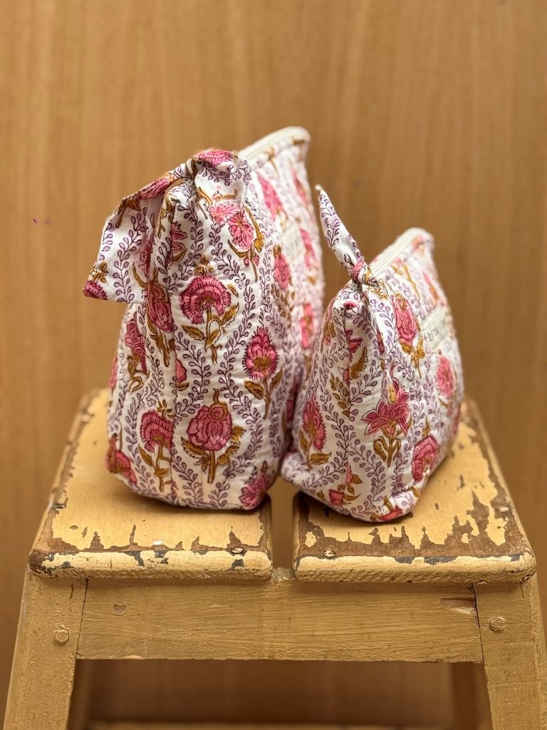 Grande et petite trousses beauté Éphèse Rose à nœud, vues de côté sur un tabouret