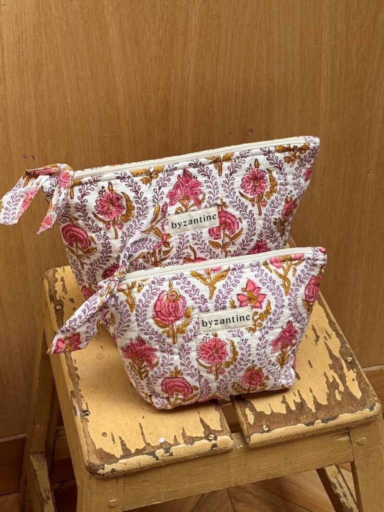 Duo de trousses beauté Éphèse Rose empilées sur un tabouret en bois