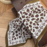 Foulard Léopard Écru et Kaki drapé sur un tabouret, bordure kaki fleurie