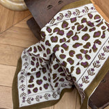 Foulard Léopard Écru et Kaki drapé sur un tabouret, bordure kaki fleurie