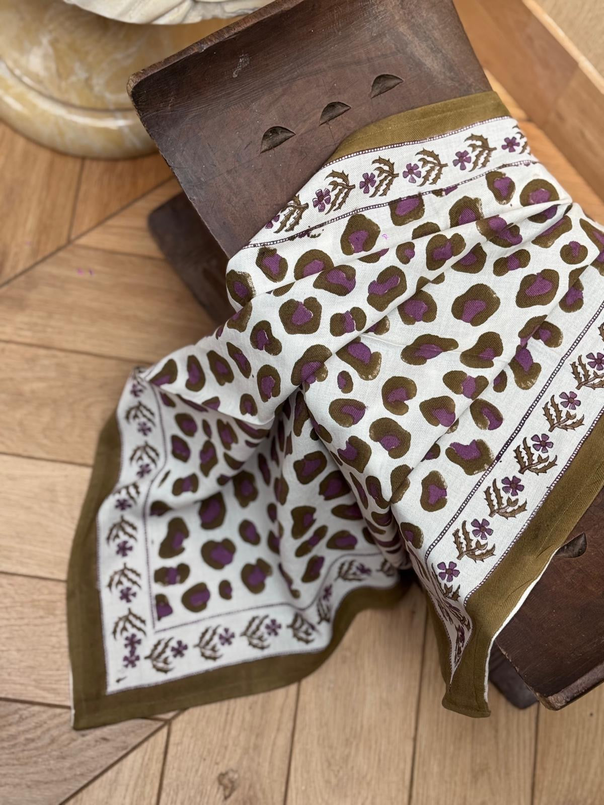 Foulard Léopard Écru et Kaki drapé sur un tabouret, bordure kaki fleurie