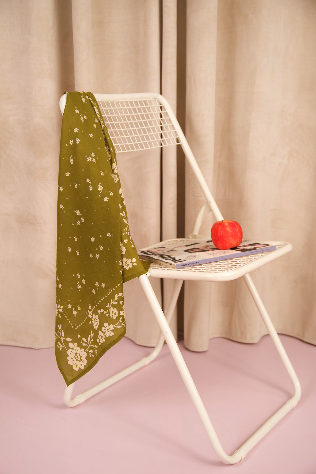 Foulard Antonia Kaki en voile de coton posé sur une chaise blanche, avec une pomme