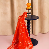 Foulard Antonia Tomato drapé sur un guéridon bleu marine