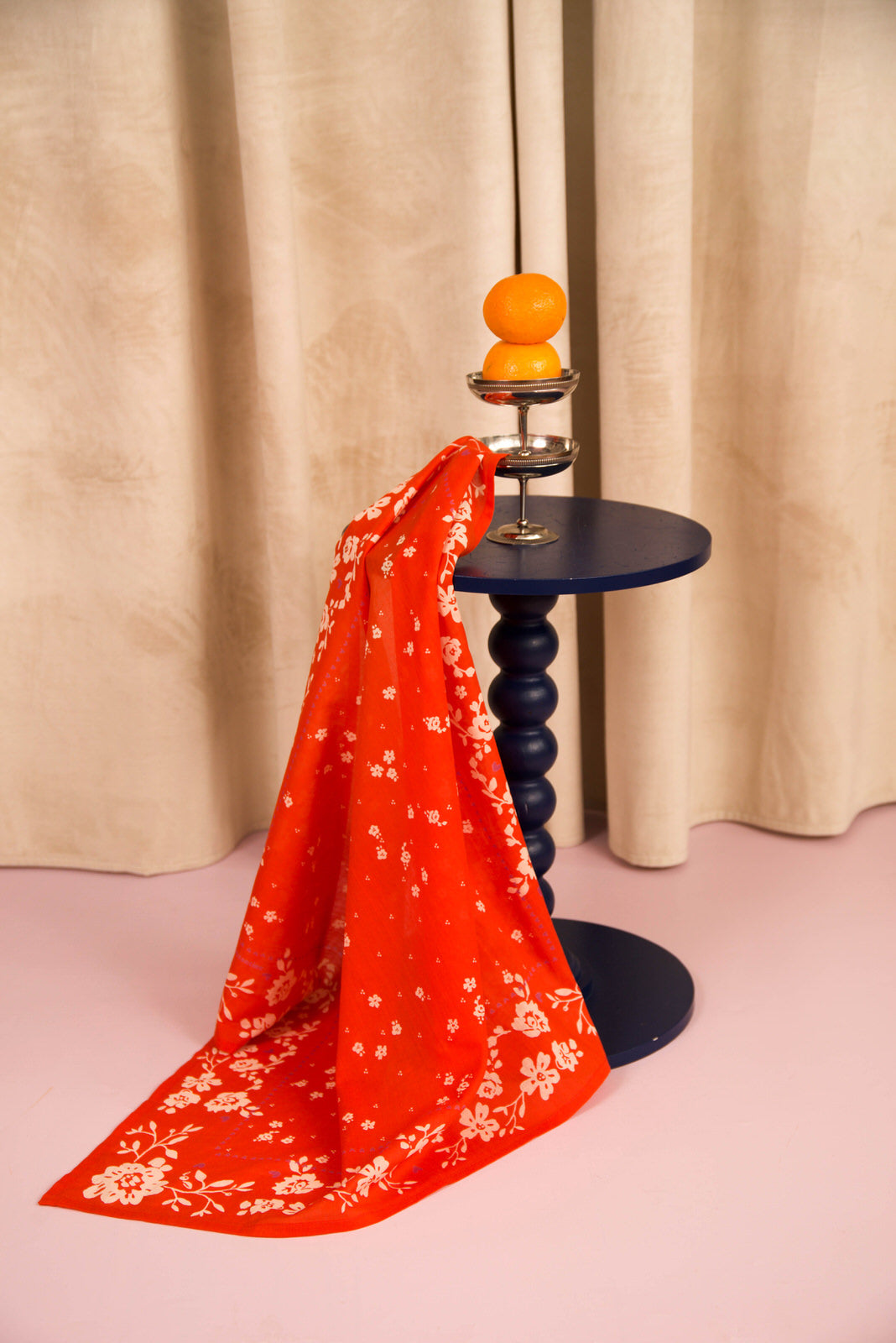 Foulard Antonia Tomato drapé sur un guéridon bleu marine