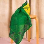Foulard Antonia Vert noué sur un tabouret, avec un filet jaune