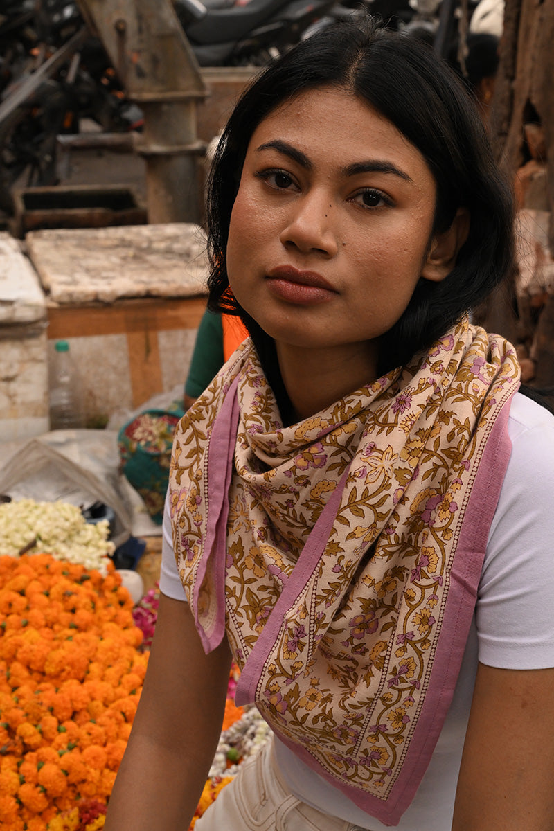 Grand foulard Calypso Lilas porté au cou sur un marché de fleurs