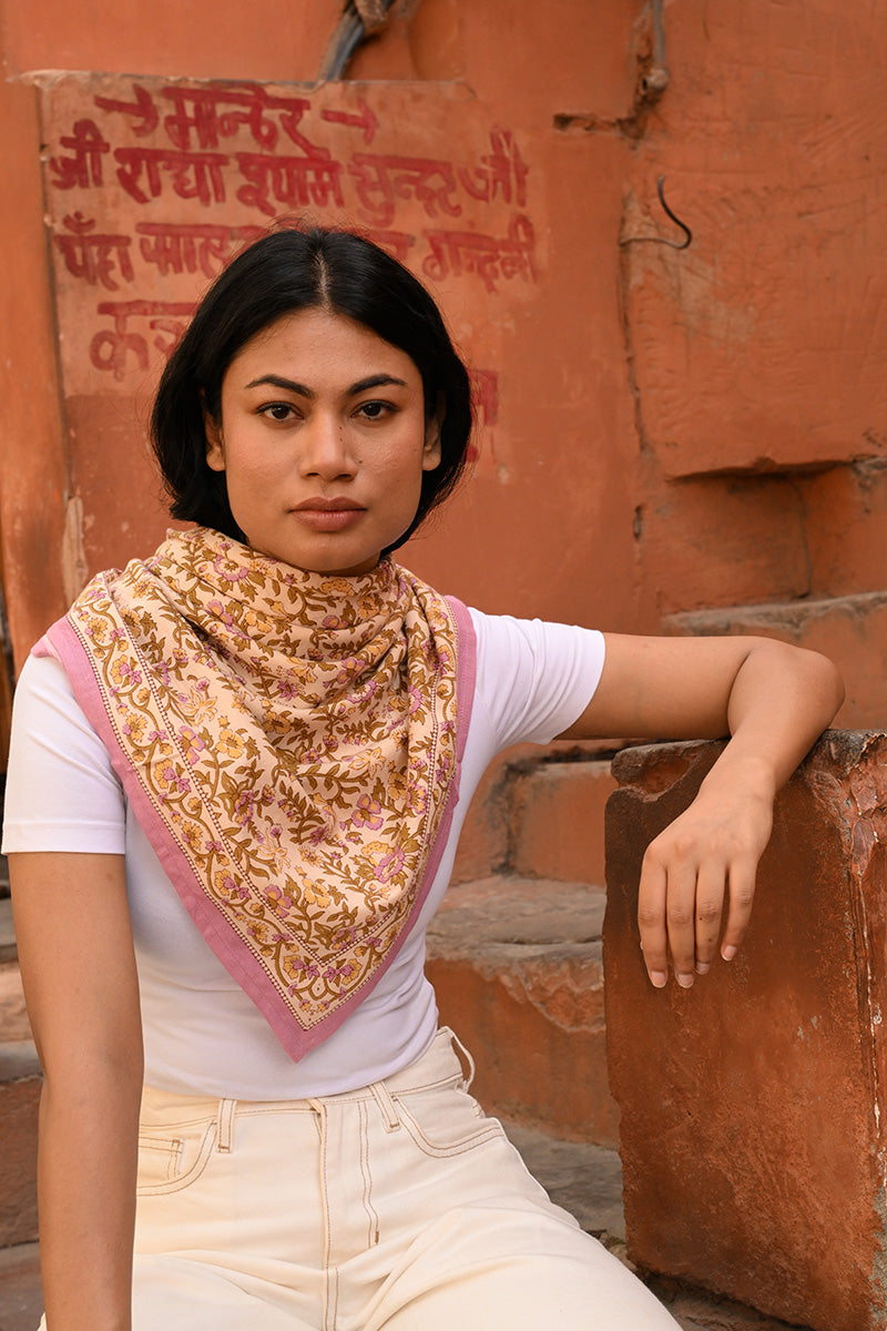 Grand foulard Calypso Lilas porté au cou, appuyée contre un mur