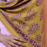 Gros plan sur le grand foulard Galatie Caramel porté sur l'épaule