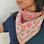 grand foulard hélios rose de byzantine, noué autour du cou d'une jeune femme habillée de bleu