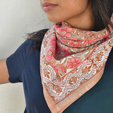 grand foulard hélios rose de byzantine, noué autour du cou d'une jeune femme habillée de bleu