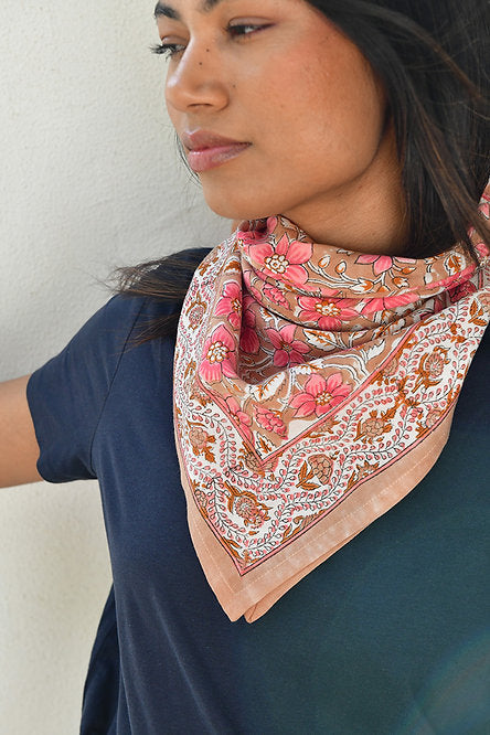 grand foulard hélios rose de byzantine, noué autour du cou d'une jeune femme habillée de bleu