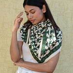 Grand foulard écru et vert à motif oiseaux porté par une femme