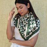 Grand foulard écru et vert à motif oiseaux porté par une femme