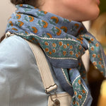Gros plan sur le grand foulard Séléné Bleu horizon noué, salopette écrue