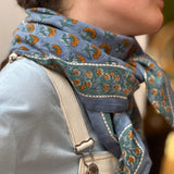Gros plan sur le grand foulard Séléné Bleu horizon noué, salopette écrue