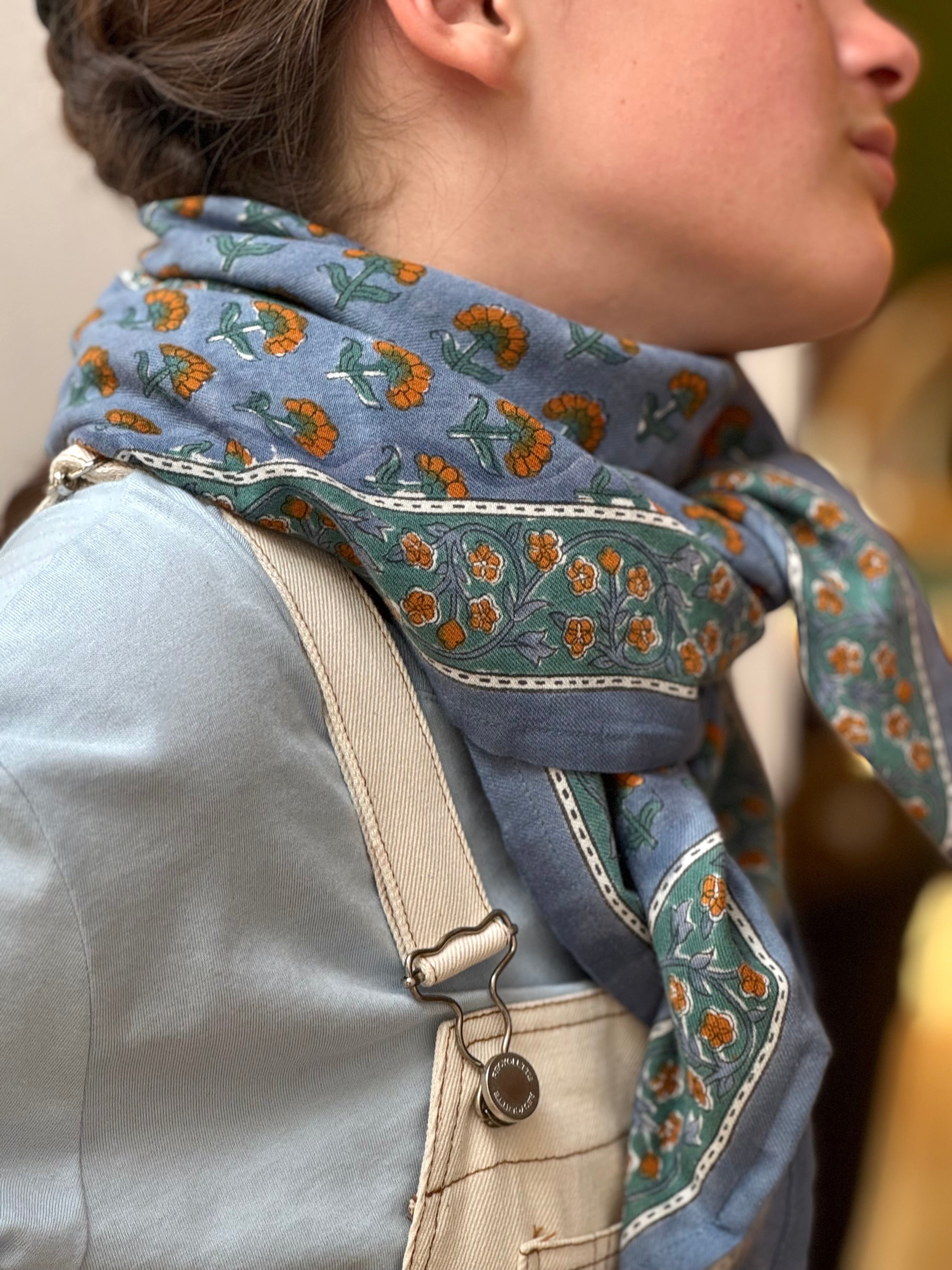 Gros plan sur le grand foulard Séléné Bleu horizon noué, salopette écrue