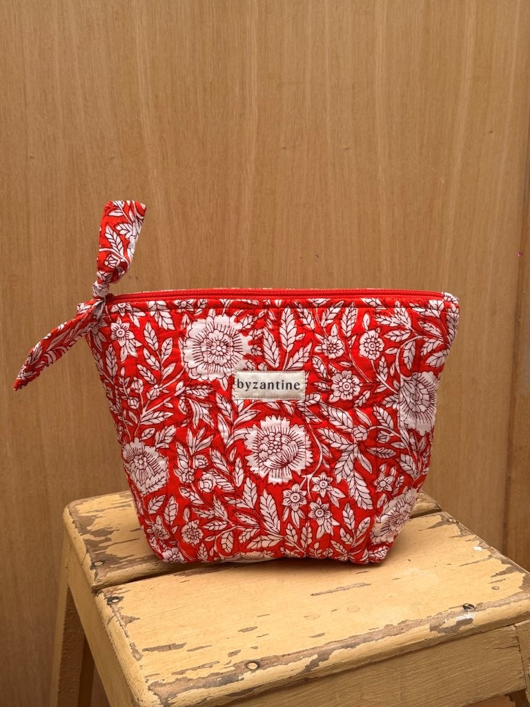 Grande trousse beauté Antioche Tomato à nœud, imprimé fleuri rouge, sur un tabouret en bois