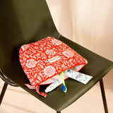 Grande trousse beauté Antioche Tomato ouverte sur une chaise verte, avec du dentifrice