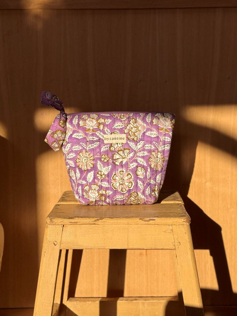 Grande trousse beauté Carthage Lilas à nœud, imprimé fleuri lilas et moutarde, sur un tabouret