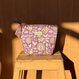 Grande trousse beauté Carthage Lilas à nœud, imprimé fleuri lilas et moutarde, sur un tabouret