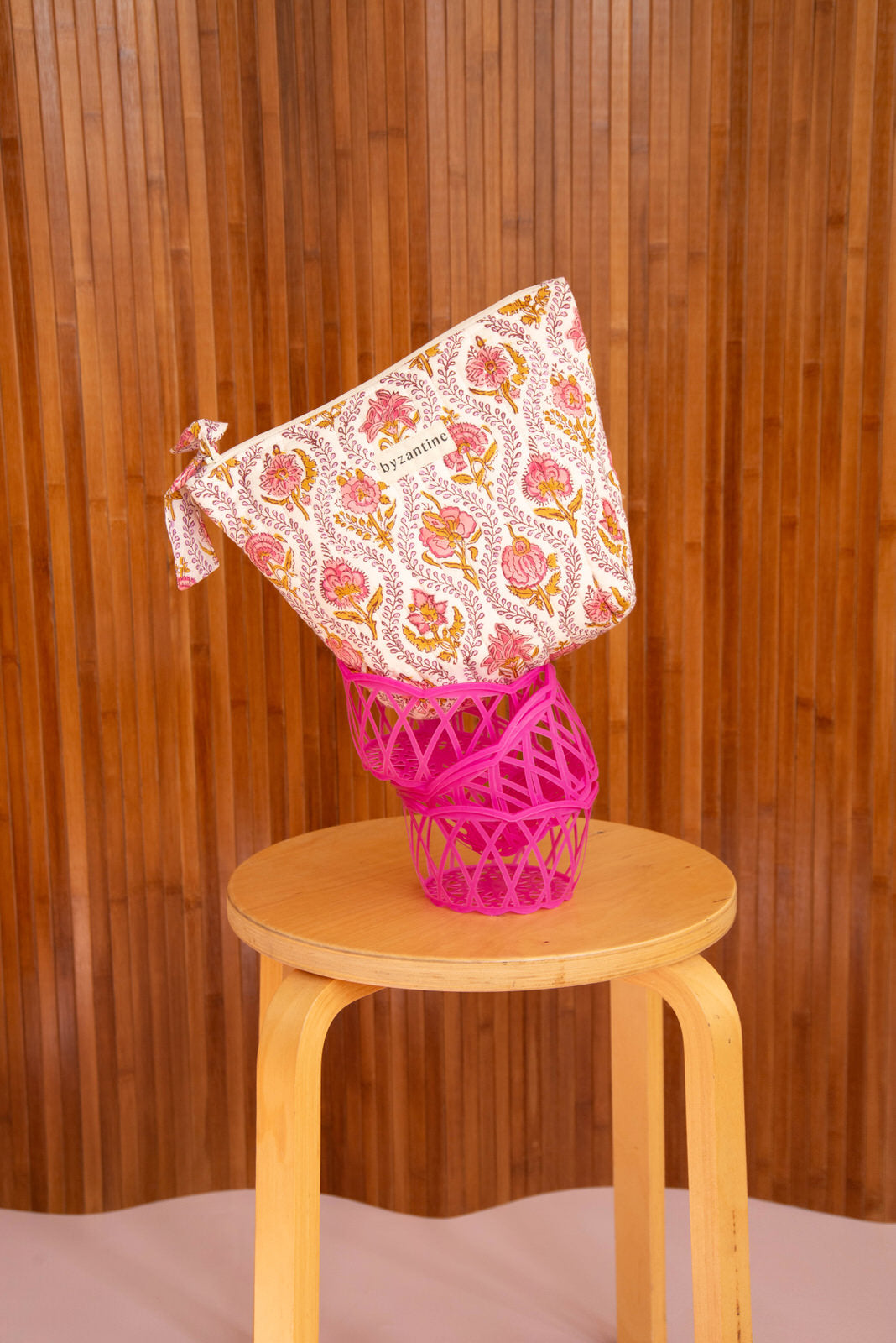 Grande trousse beauté Éphèse Rose posée sur une corbeille rose, sur un tabouret