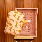 Grande trousse beauté Fauve Rose à zip moutarde posée contre une caisse rose