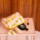 Grande trousse beauté Fauve Rose ouverte sur une caisse rose, avec peigne et parfum